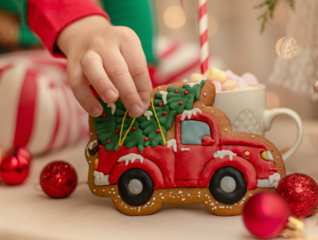 Kid with christmas cookie in shape of a truck.