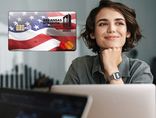 Young woman in front of computer with new debit card showing to the left of her.